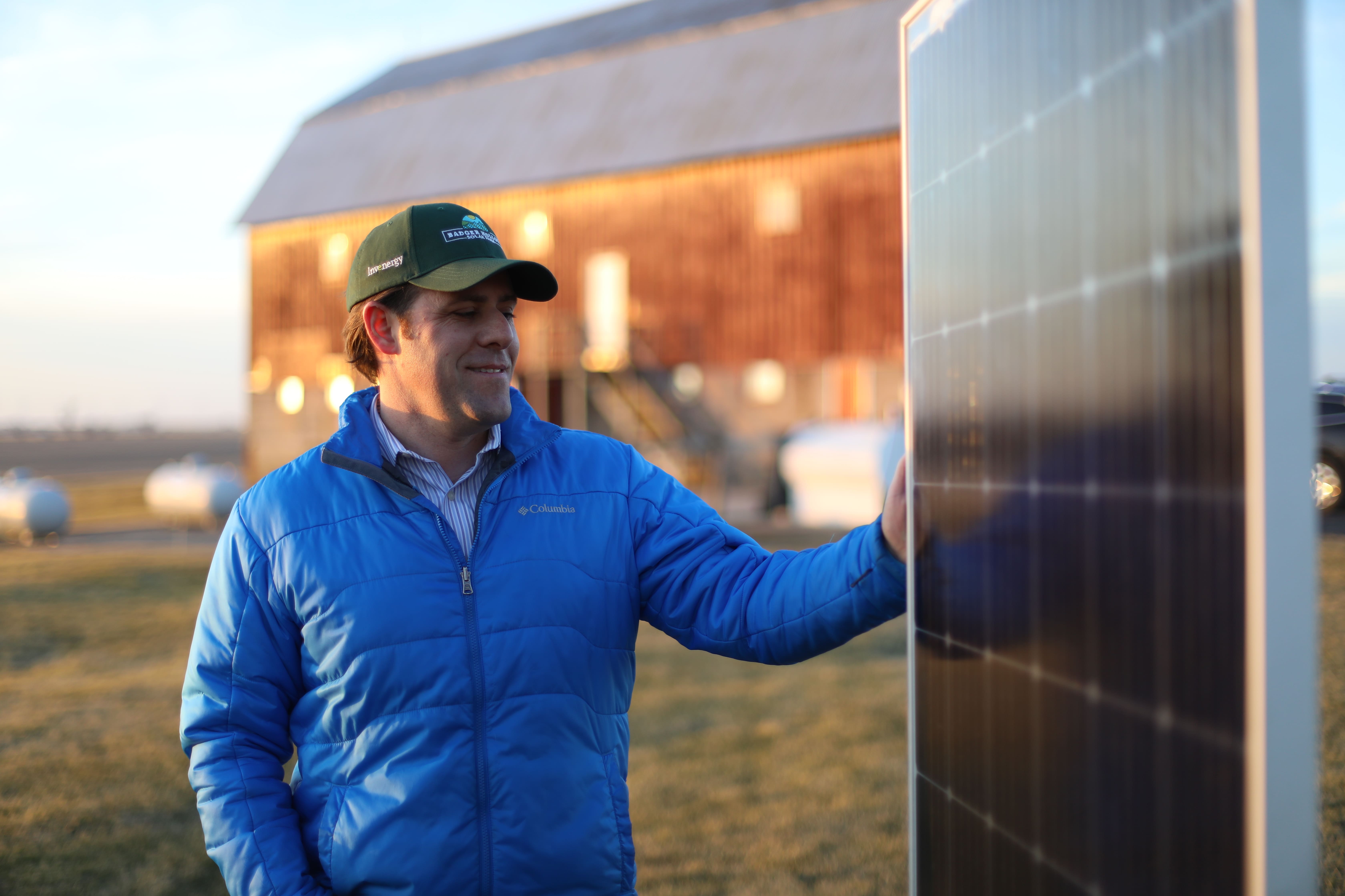 Man standing next to solar panel in field